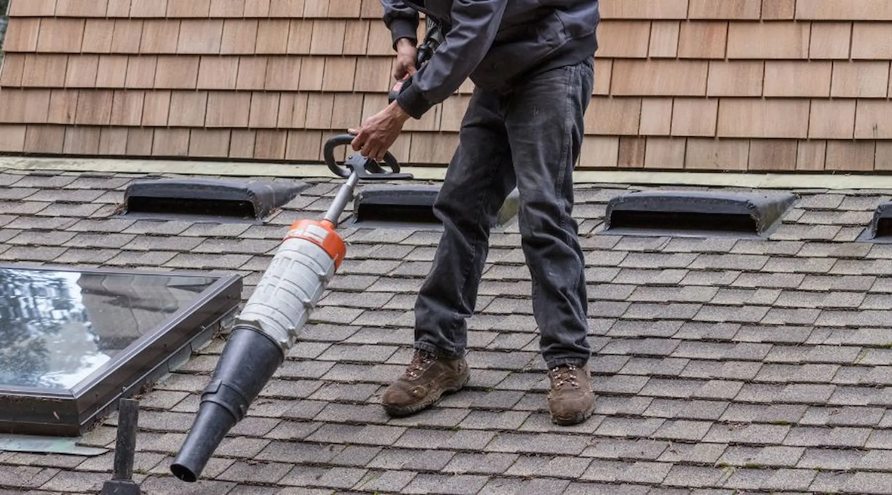 Man using a leaf blower on a roof