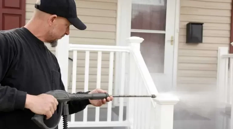 A person power washing a white vinyl porch railing