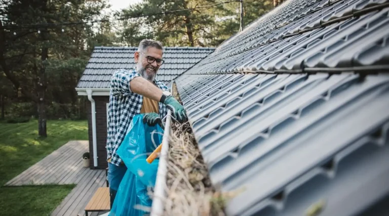 Man cleaning leaves from gutters.