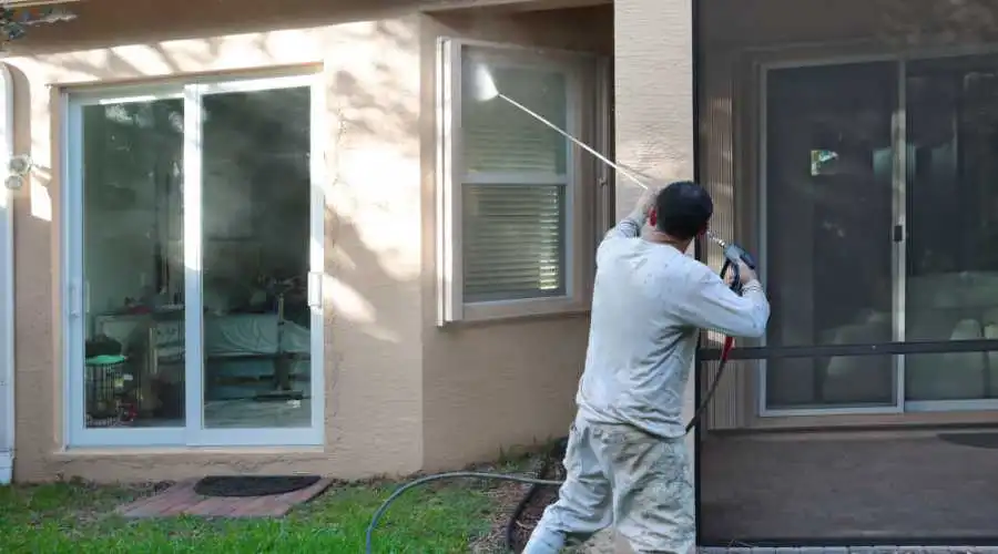 Someone power washing the exterior of a house