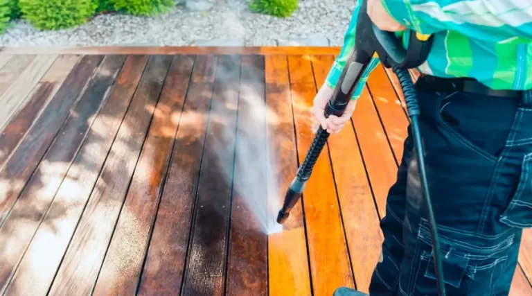 person removing deck stains using power washer