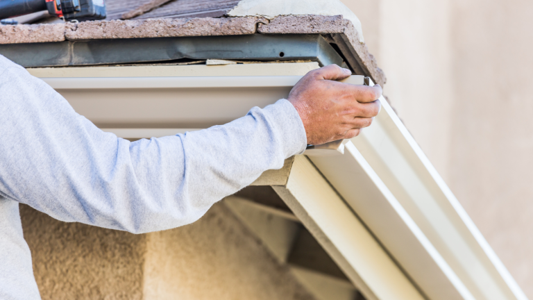 Person working on a gutter that is coming off a roof