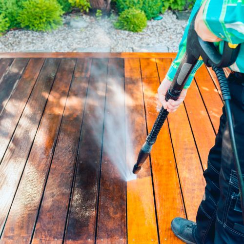 Person power washing a deck showing before and after