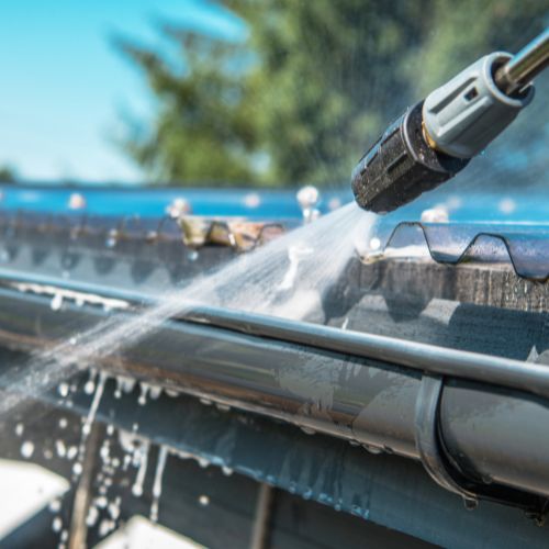 Power washer cleaning a gutter