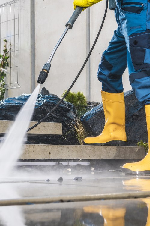 Person power washing a sidewalk