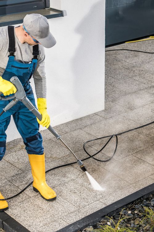 Person power washing a sidewalk